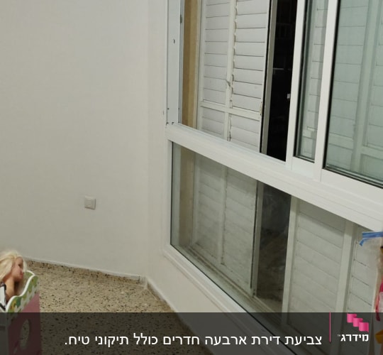 קיר לבן צבוע ליד חלון גדול עם תריסים